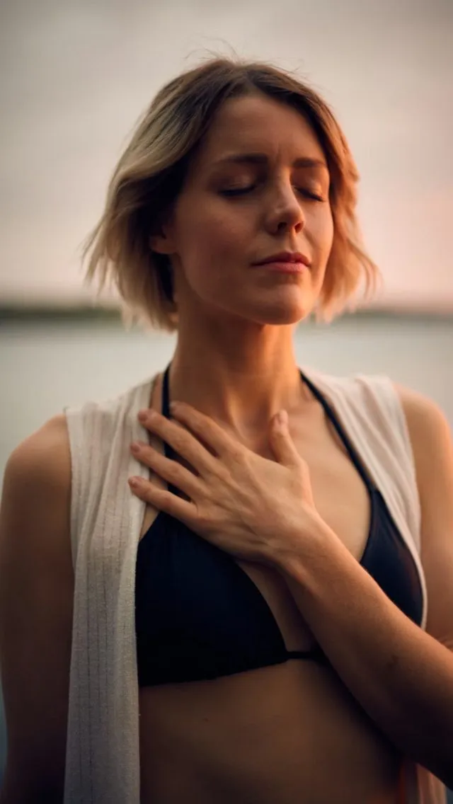 A woman with eyes closed, one hand on her chest, breathing calmly.